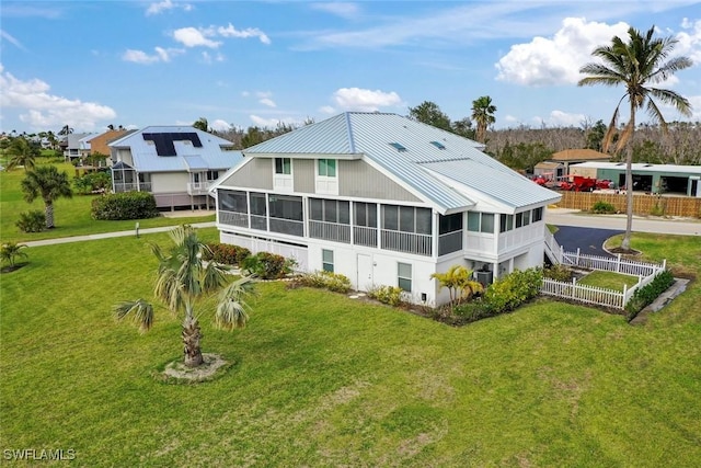 rear view of house with a sunroom, a yard, and central AC