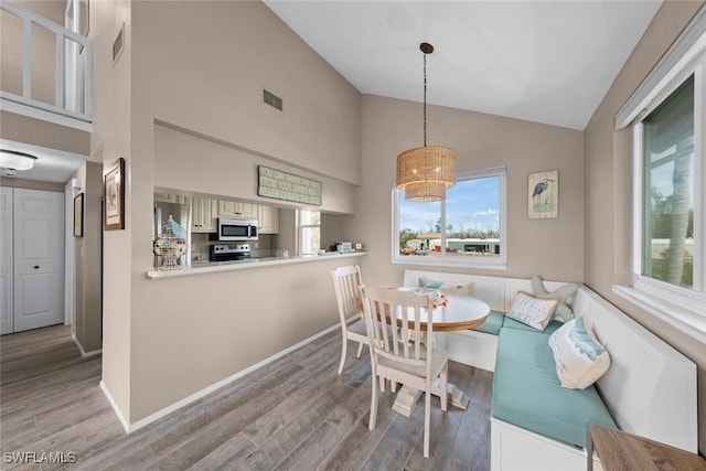 dining space featuring breakfast area, high vaulted ceiling, and light wood-type flooring