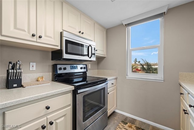kitchen with dark hardwood / wood-style floors, white cabinets, and appliances with stainless steel finishes