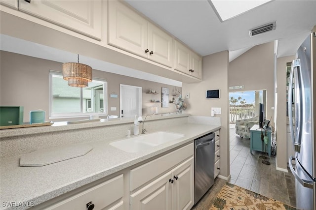 kitchen featuring appliances with stainless steel finishes, decorative light fixtures, sink, dark wood-type flooring, and a healthy amount of sunlight
