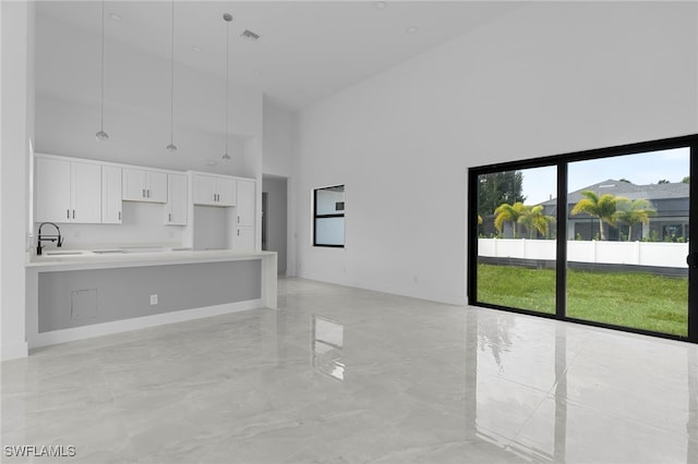 unfurnished living room featuring a towering ceiling and sink