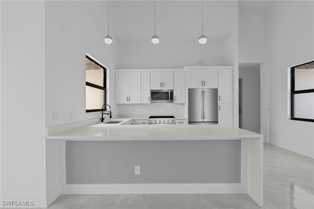 kitchen with white cabinetry, stainless steel appliances, sink, and hanging light fixtures