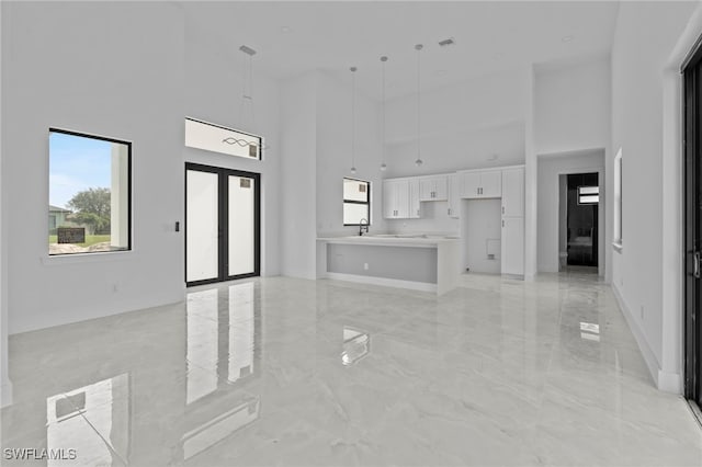 living room featuring a towering ceiling, sink, and french doors