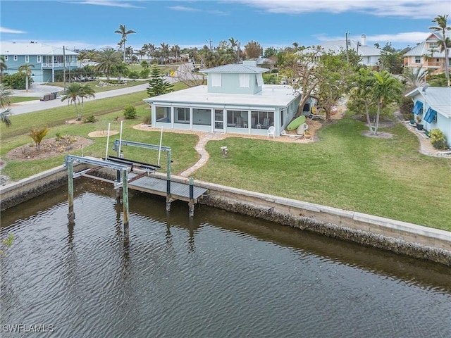 rear view of property featuring a water view, a sunroom, and a lawn