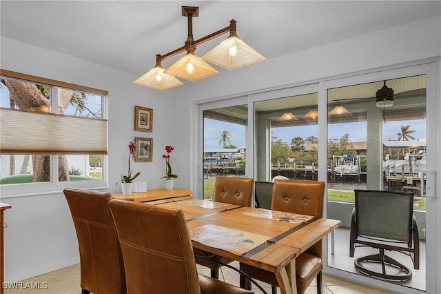 dining space featuring a water view and light tile patterned floors