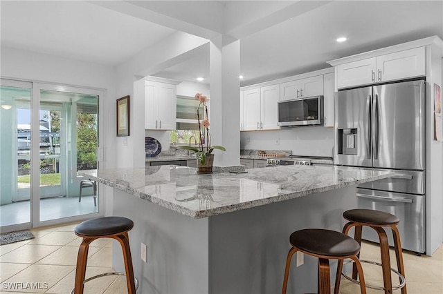 kitchen with appliances with stainless steel finishes, a kitchen bar, a center island, and white cabinets