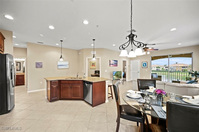 kitchen featuring sink, a kitchen island with sink, hanging light fixtures, stainless steel appliances, and light stone countertops