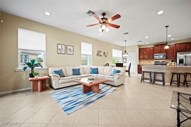 living room with ceiling fan, a wealth of natural light, and light tile patterned floors