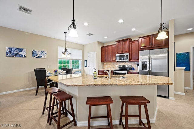 kitchen with light tile patterned flooring, a kitchen bar, tasteful backsplash, pendant lighting, and stainless steel appliances