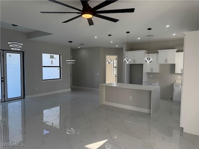 kitchen with pendant lighting, ceiling fan, a center island, and white cabinets