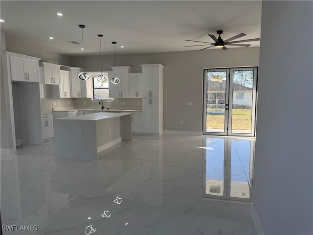 kitchen with light countertops, decorative light fixtures, white cabinetry, and a center island