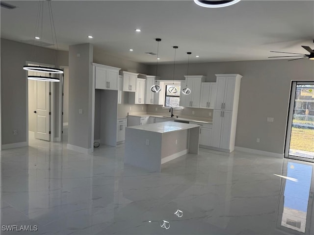 kitchen featuring a center island, light countertops, a sink, and white cabinetry