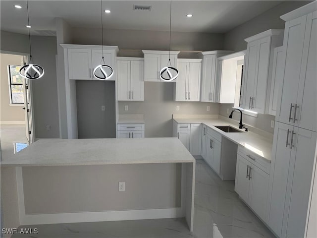 kitchen with hanging light fixtures, white cabinetry, a kitchen island, and sink