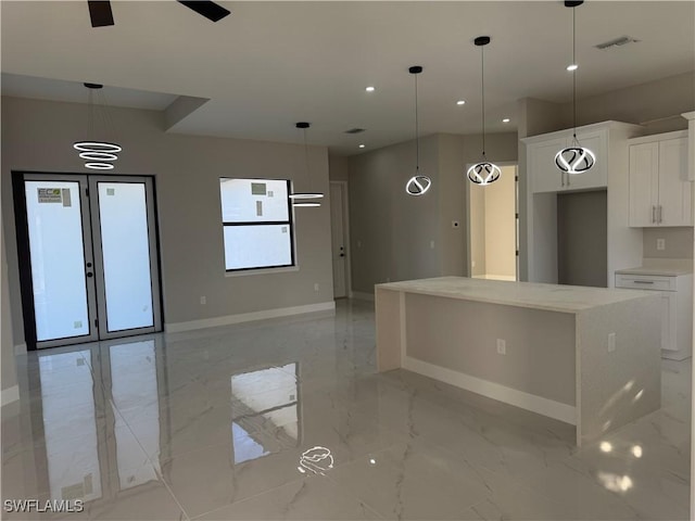 kitchen featuring marble finish floor, a kitchen island, visible vents, and white cabinets