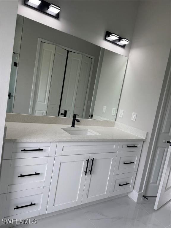 full bath featuring a closet, vanity, and marble finish floor