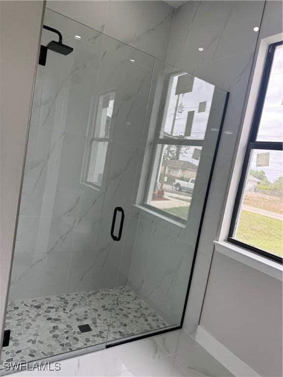 full bath with marble finish floor, a marble finish shower, and a wealth of natural light