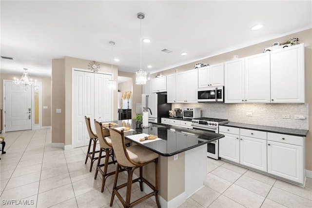 kitchen featuring decorative light fixtures, dark countertops, white microwave, white cabinets, and high end stove