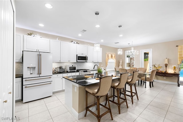 kitchen featuring white cabinets, high end white refrigerator, a kitchen island with sink, and pendant lighting