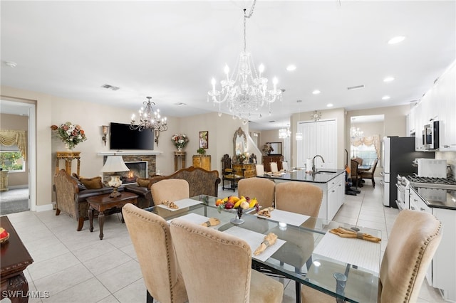 dining space with recessed lighting, visible vents, light tile patterned flooring, a chandelier, and a lit fireplace