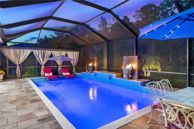 pool at dusk featuring a lanai, a patio area, and an outdoor pool