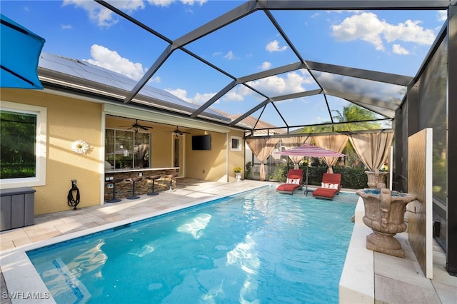 pool featuring glass enclosure, fence, a ceiling fan, an outdoor bar, and a patio area