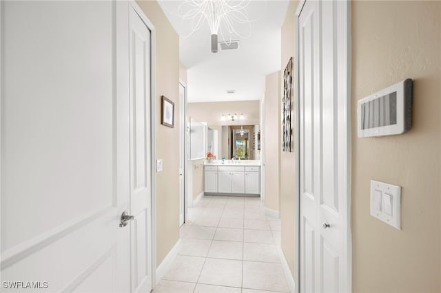 corridor featuring light tile patterned flooring, visible vents, and baseboards