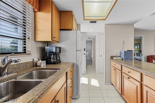 kitchen featuring stone countertops, sink, and light tile patterned floors