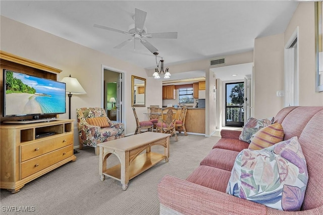 carpeted living room featuring ceiling fan with notable chandelier