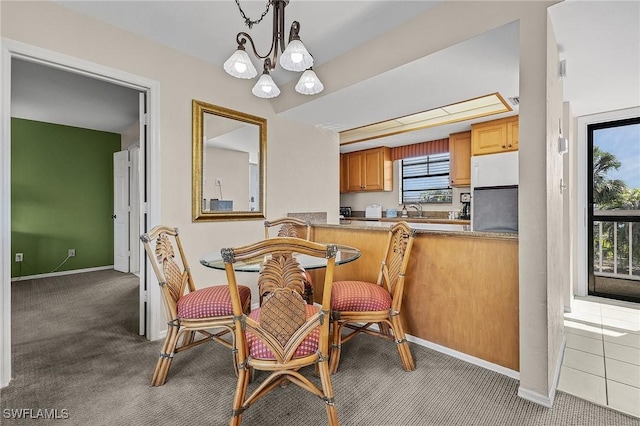 dining area with carpet floors, sink, and an inviting chandelier