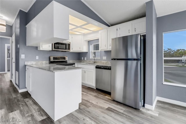 kitchen with vaulted ceiling, sink, white cabinets, light hardwood / wood-style floors, and stainless steel appliances