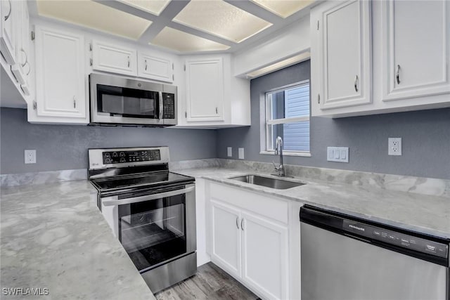 kitchen featuring sink, stainless steel appliances, white cabinets, and light stone countertops