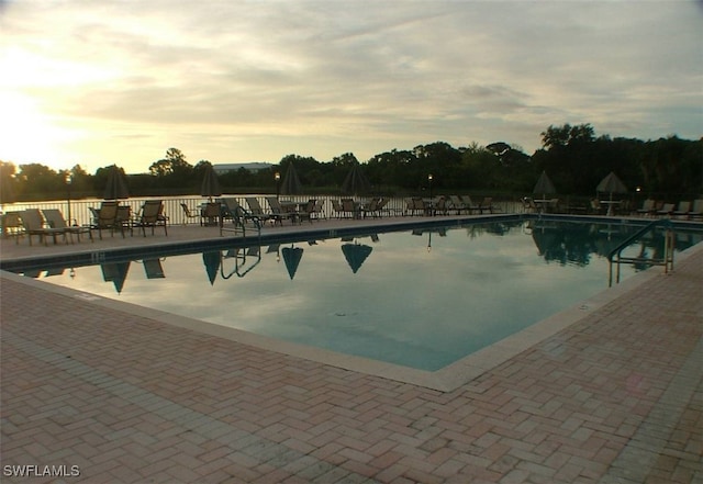 pool at dusk featuring a patio