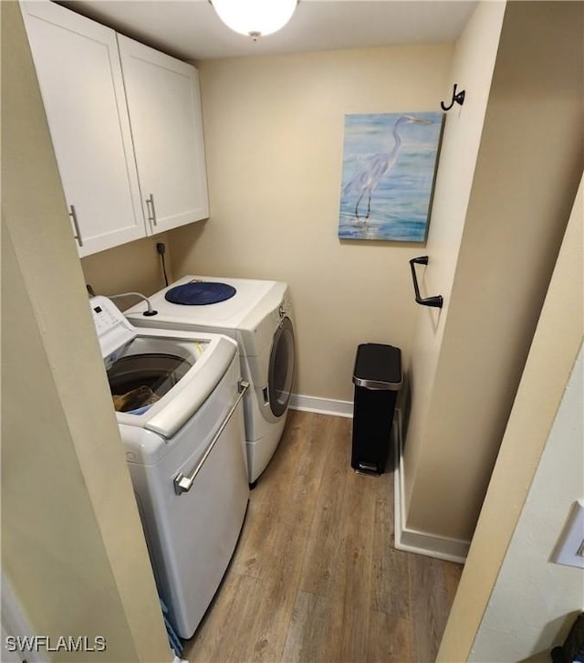 laundry area featuring washer and dryer, cabinets, and light hardwood / wood-style flooring