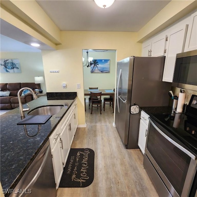 kitchen featuring white cabinets, appliances with stainless steel finishes, dark stone countertops, sink, and light wood-type flooring