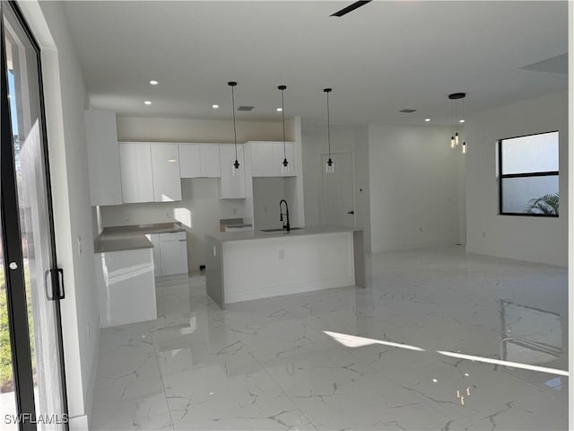 kitchen featuring sink, white cabinetry, decorative light fixtures, an island with sink, and a wealth of natural light