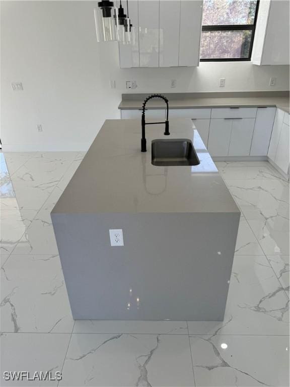 kitchen with white cabinetry, sink, and an island with sink