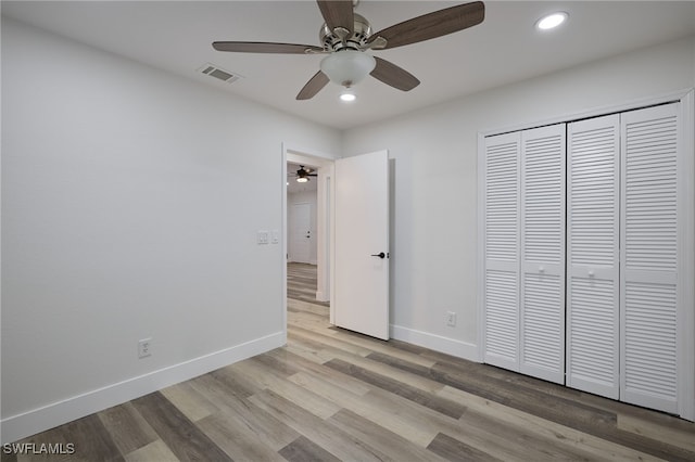 unfurnished bedroom featuring ceiling fan, a closet, and light wood-type flooring