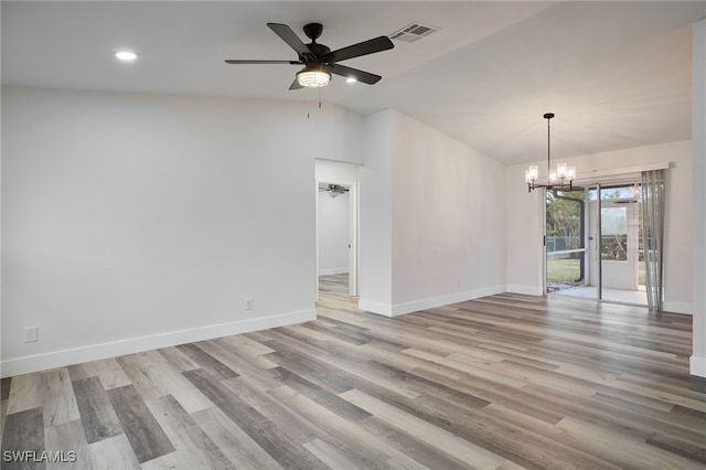 spare room featuring vaulted ceiling, ceiling fan with notable chandelier, and light hardwood / wood-style floors