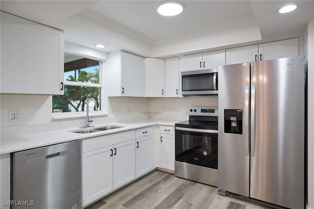 kitchen with sink, white cabinets, a raised ceiling, ornamental molding, and stainless steel appliances