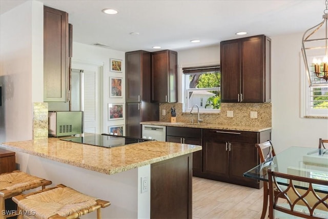 kitchen with kitchen peninsula, pendant lighting, light stone counters, a kitchen bar, and decorative backsplash