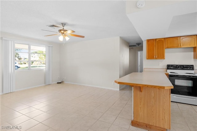 kitchen featuring light tile patterned floors, range with electric cooktop, a kitchen breakfast bar, and ceiling fan