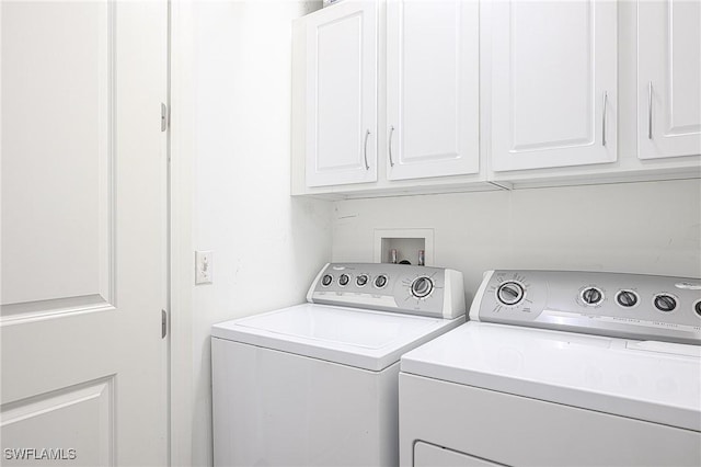 clothes washing area with cabinets and washer and dryer