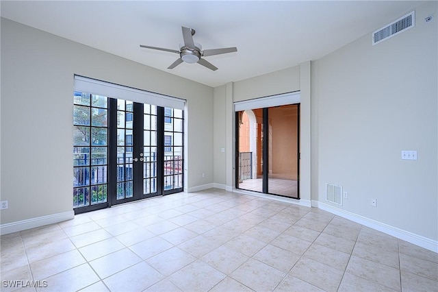 tiled empty room featuring ceiling fan and french doors