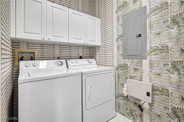 clothes washing area with washer and dryer, electric panel, and cabinets