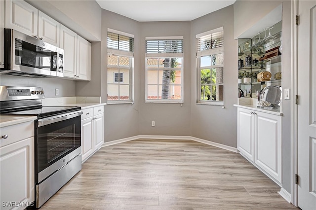 kitchen featuring stainless steel appliances, white cabinets, and light wood-type flooring