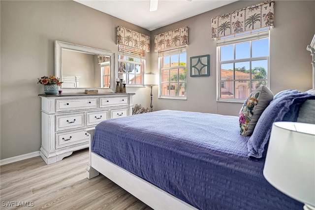 bedroom with multiple windows, ceiling fan, and light wood-type flooring