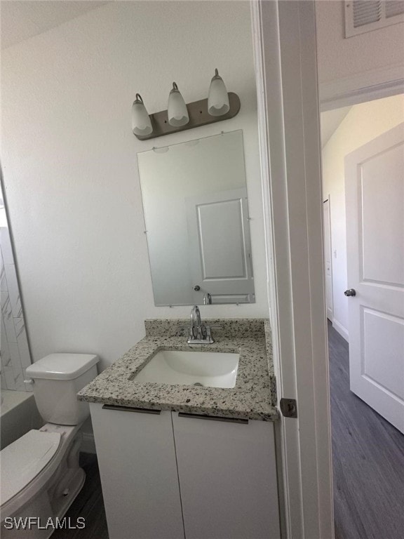 bathroom with wood-type flooring, toilet, vanity, and a bathing tub