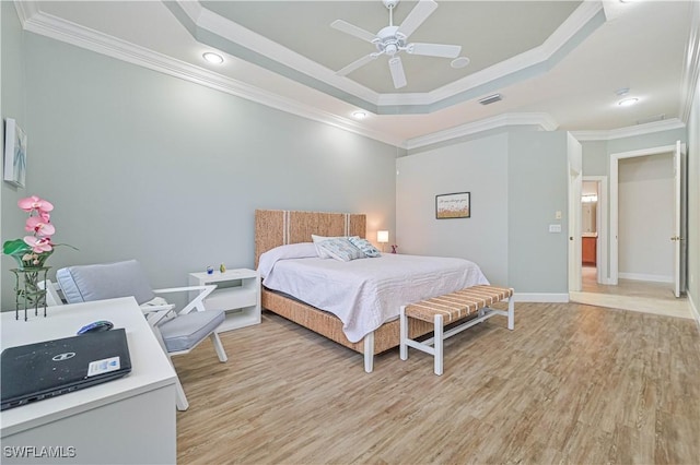 bedroom with ornamental molding, light hardwood / wood-style floors, ceiling fan, and a raised ceiling