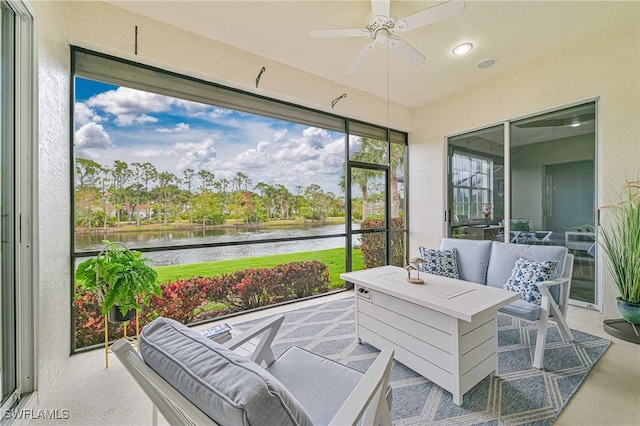 sunroom featuring a water view and ceiling fan