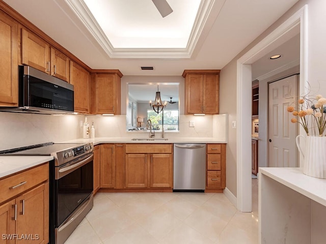 kitchen with brown cabinetry, stainless steel appliances, a sink, and light countertops